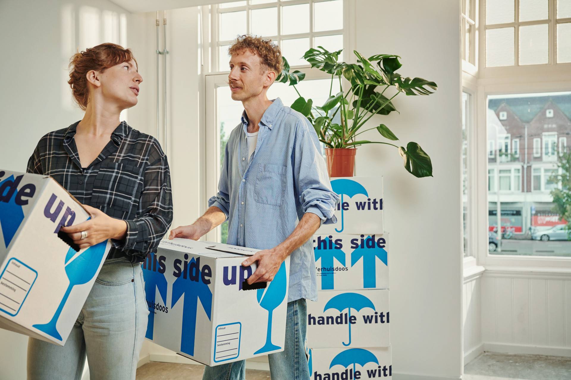 Twee mensen verhuizen dozen in een lichte kamer.