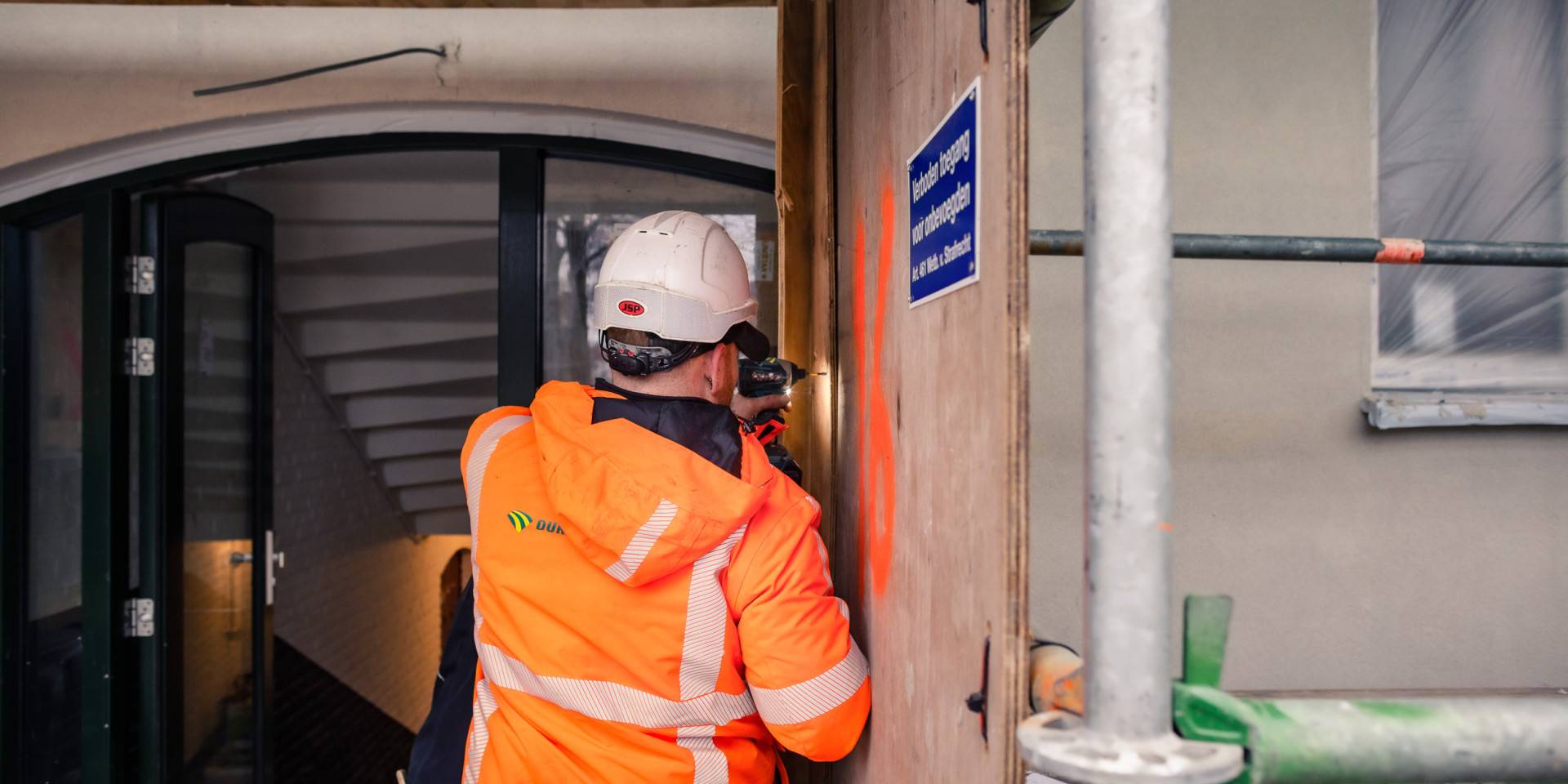 Bouwvakker in felgekleurd jack aan het werk.